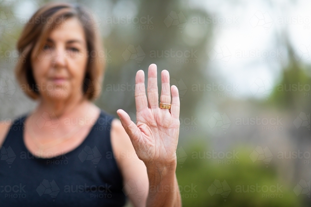 mature woman with hand up in a gesture which indicates to stop - Australian Stock Image