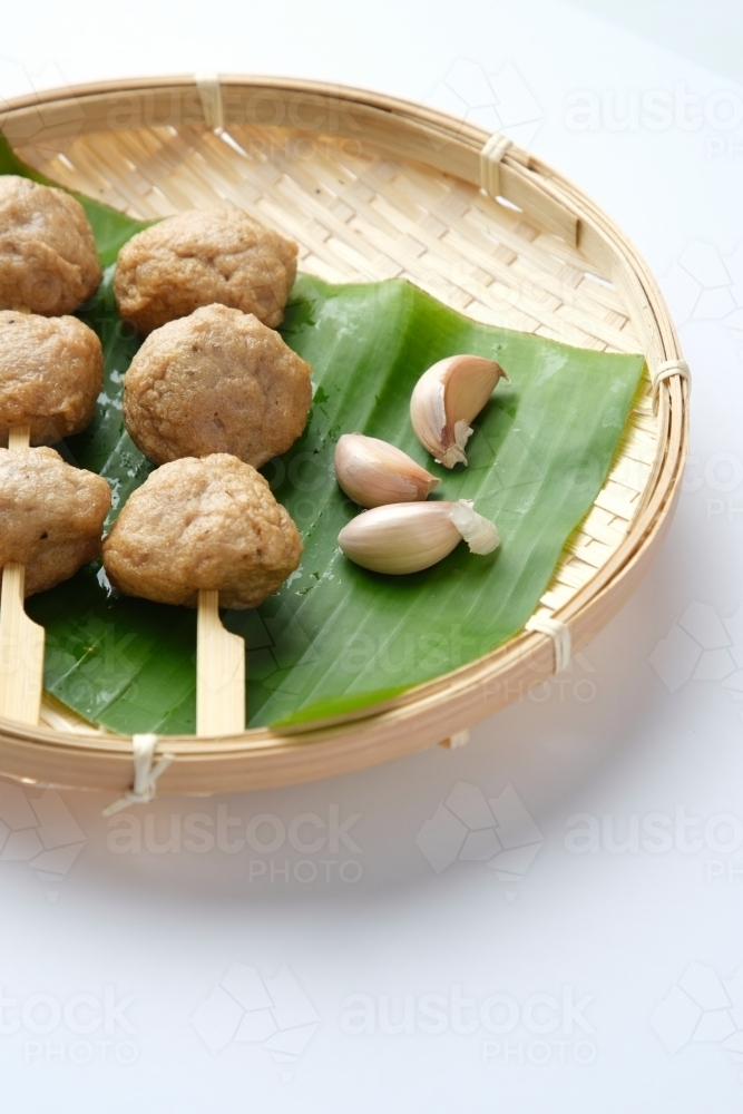 Meatballs on skewers served on a banana leaf inside the shallow woven basket. - Australian Stock Image