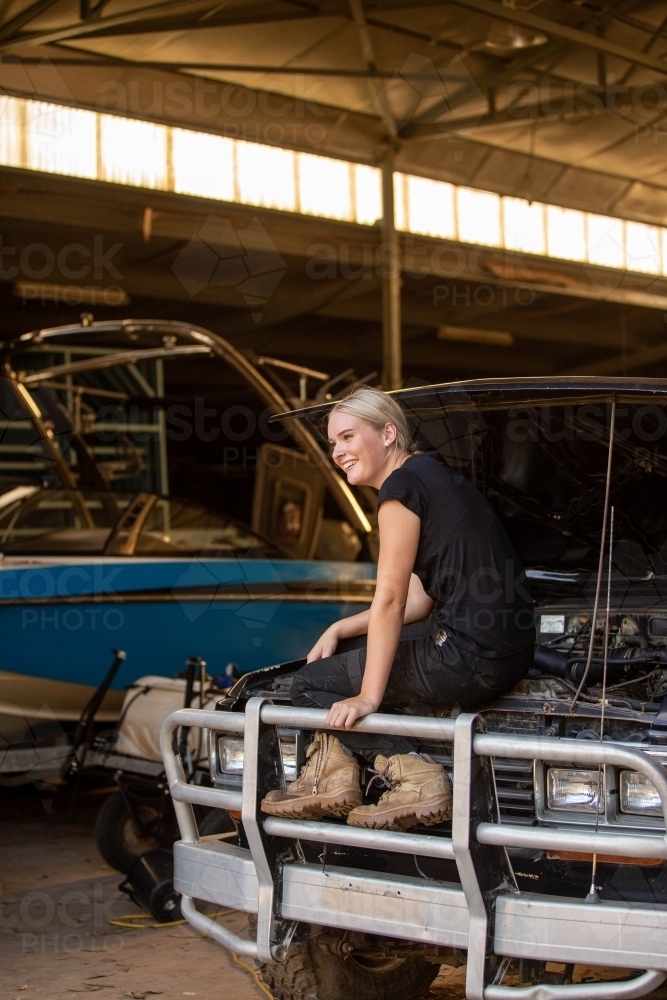 Mechanic sitting on the front of a 4wd looking away - Australian Stock Image