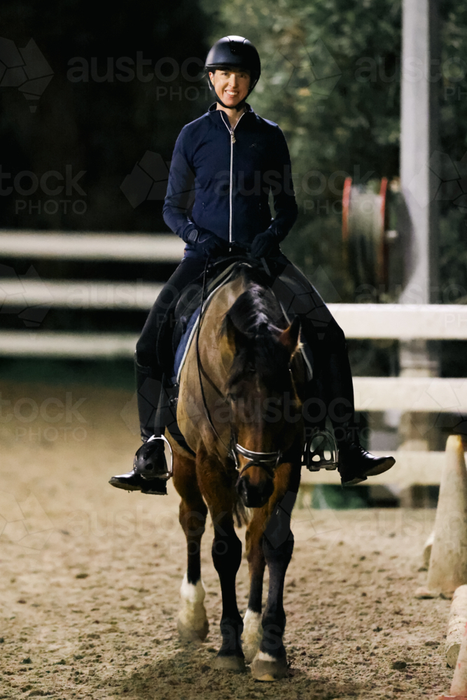 MELBOURNE, AUSTRALIA - July 26 2023: A female practices on her horse in an arena at night - Australian Stock Image