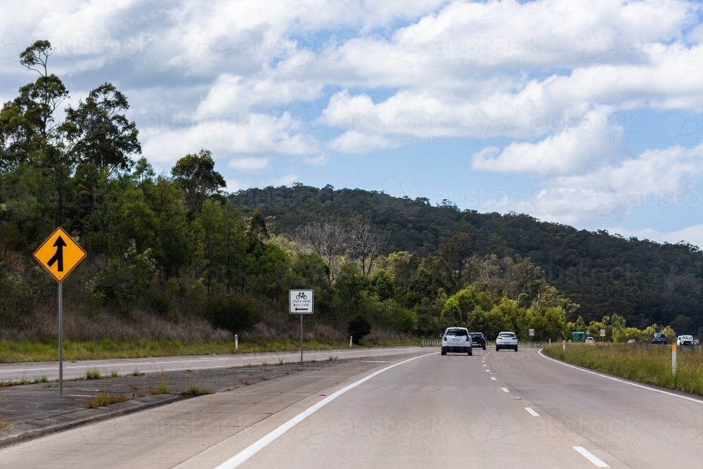 Merging onto highway lane for cars and sign about cyclists - Australian Stock Image