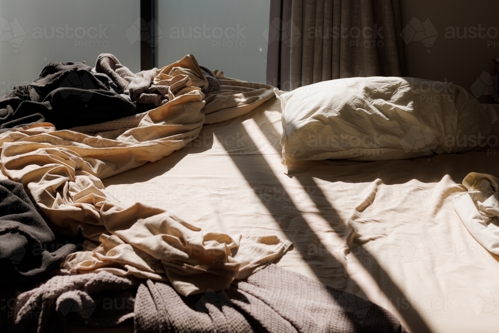 Messy unmade bed in the early morning - Australian Stock Image