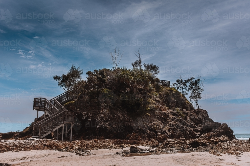 Metal staircase with multiple levels attached to a large rock formation. - Australian Stock Image