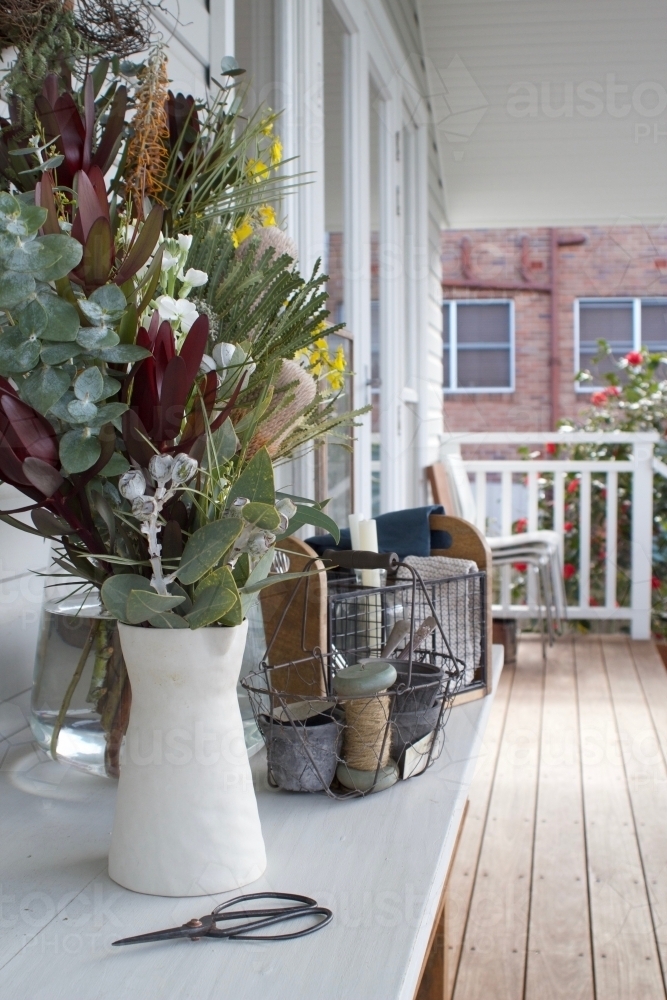 Exterior view of house with veranda, table with vase of flowers - Australian Stock Image