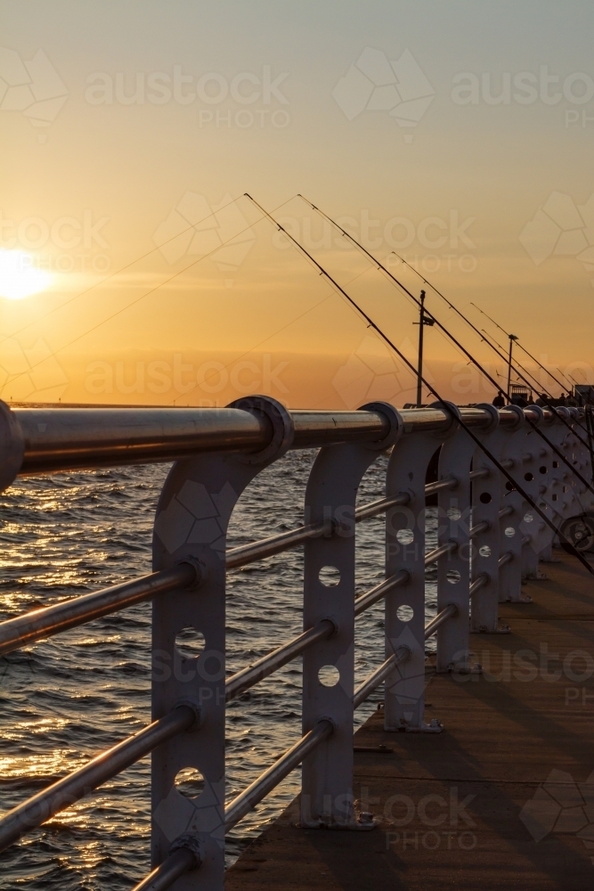 Fishing rods lined up on St Kilda pier at sunset - Australian Stock Image