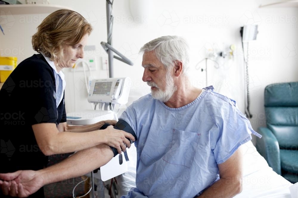 Middle aged male patient being treated by a nurse in a hospital ward - Australian Stock Image