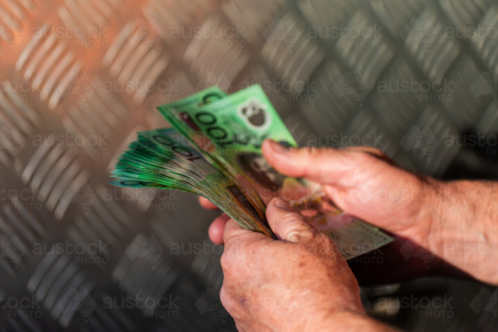 Middle aged man holding hundreds of dollars of Australian cash beside meal tool box on ute - Australian Stock Image