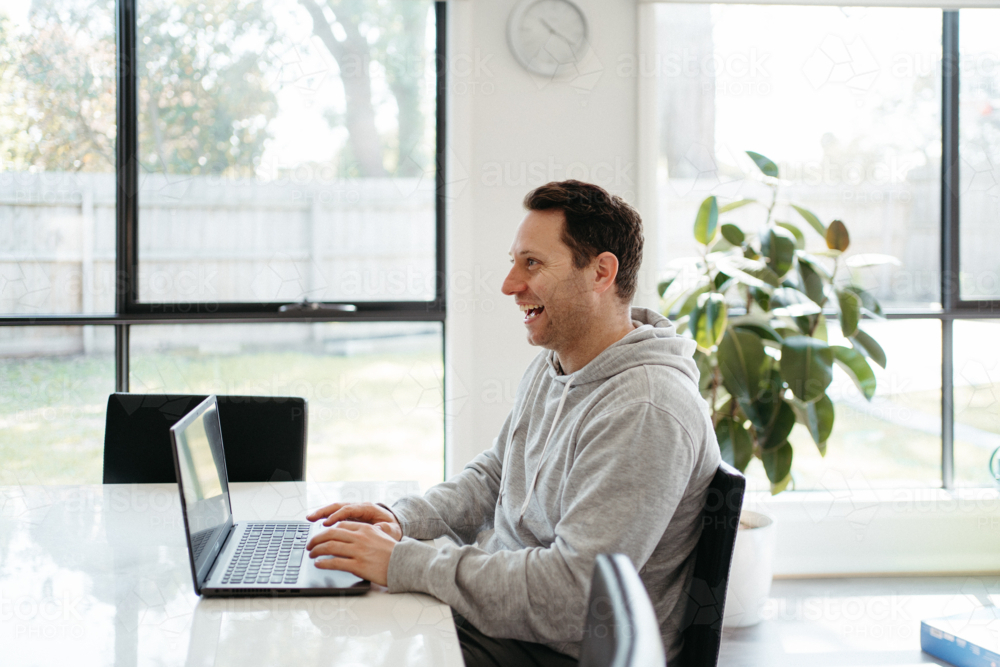 Middle-aged man working on his laptop on the dining table. - Australian Stock Image