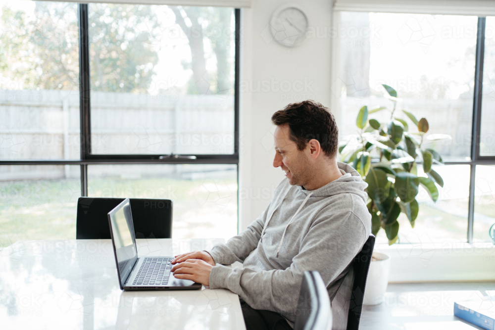 Middle-aged man working on his laptop on the dining table. - Australian Stock Image