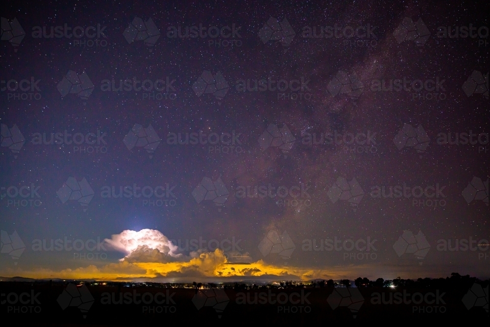 milky way with a storm cloud lit up by lightening in the frame - Australian Stock Image