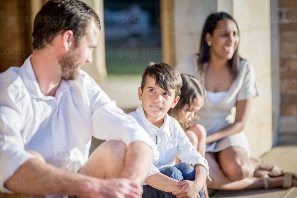 Mixed race aboriginal and caucasian family sitting together son looking at father - Australian Stock Image