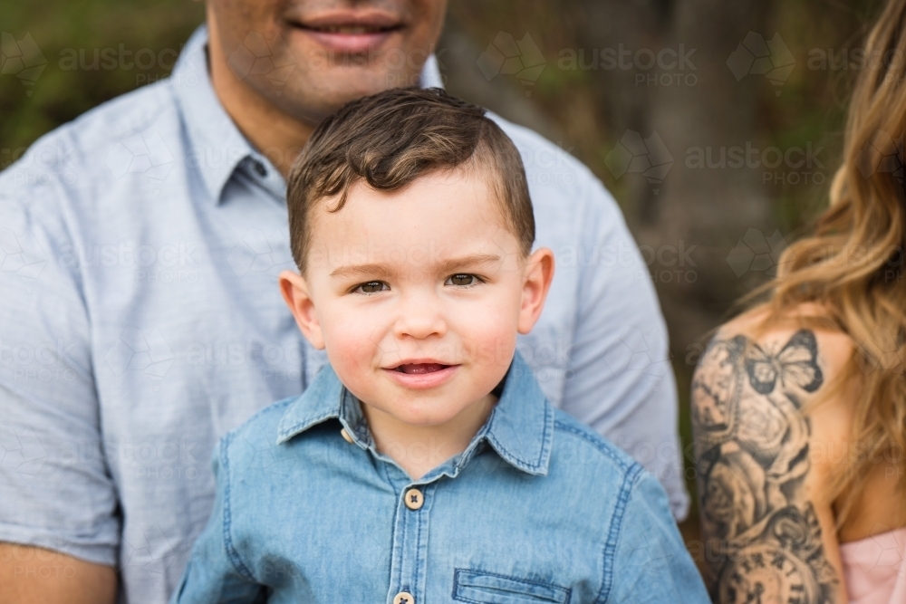 Mixed race aboriginal caucasian young boy smiling sitting on dad's lap - Australian Stock Image