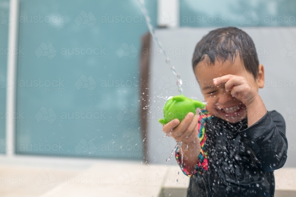 Mixed race boy playing in small backyard pool - Australian Stock Image