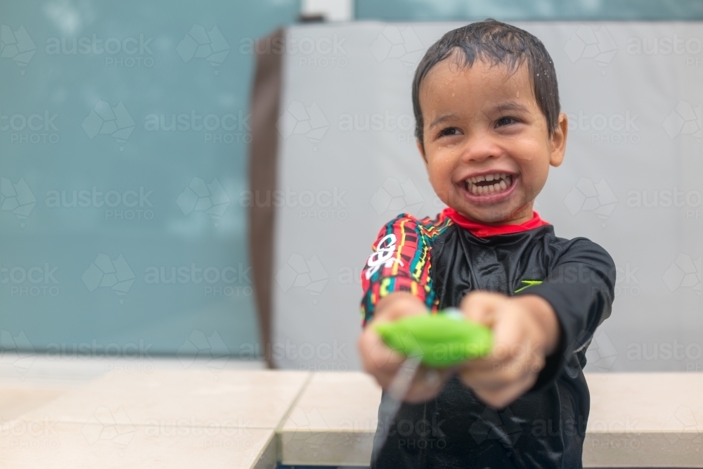 Mixed race boy playing in small backyard pool - Australian Stock Image