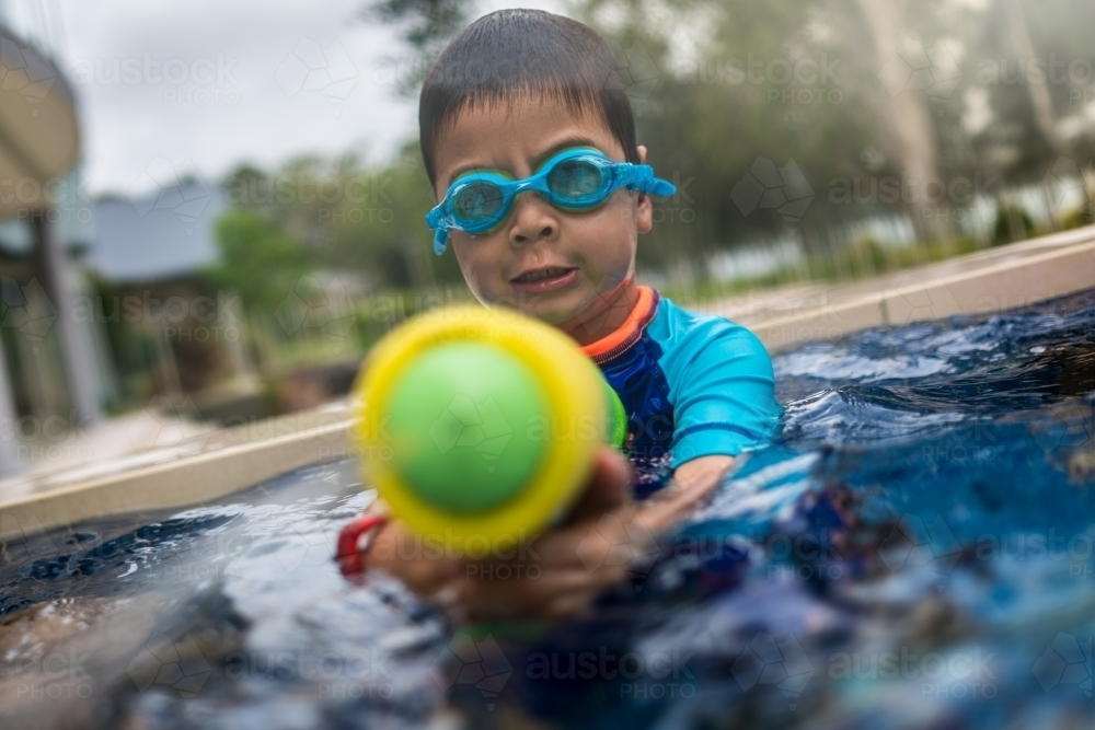 Mixed race boy playing in small backyard pool - Australian Stock Image