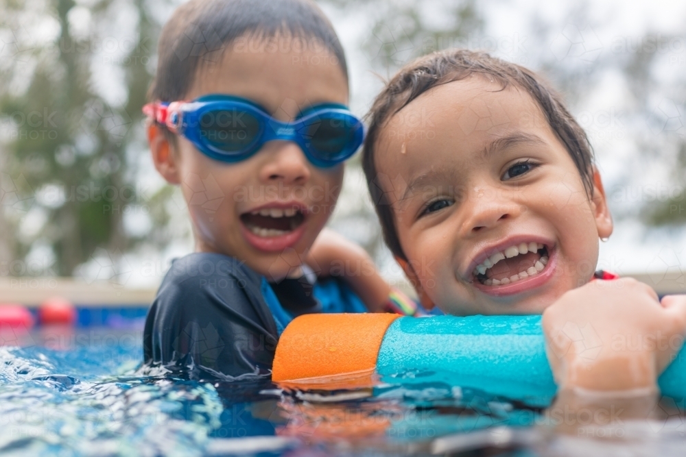 Mixed race boys playing in small backyard pool - Australian Stock Image