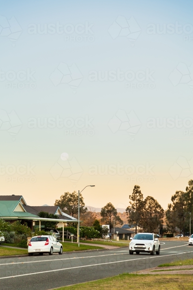 Moon in sky at dusk over suburban street in singleton - Australian Stock Image