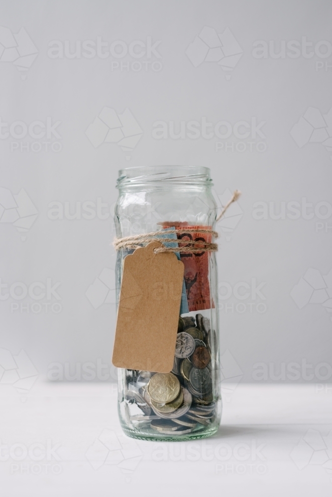 Money jar with australian money and a blank tag - Australian Stock Image