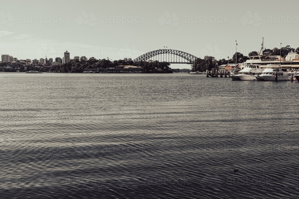 Monochromatic view of Sydney Harbour Bridge and cbd from afar, across the bay - Australian Stock Image