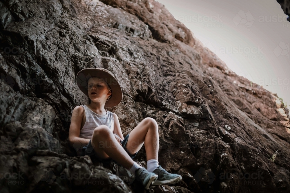 Moody image of young boy exploring cave by the beach in the Whitsundays - Australian Stock Image