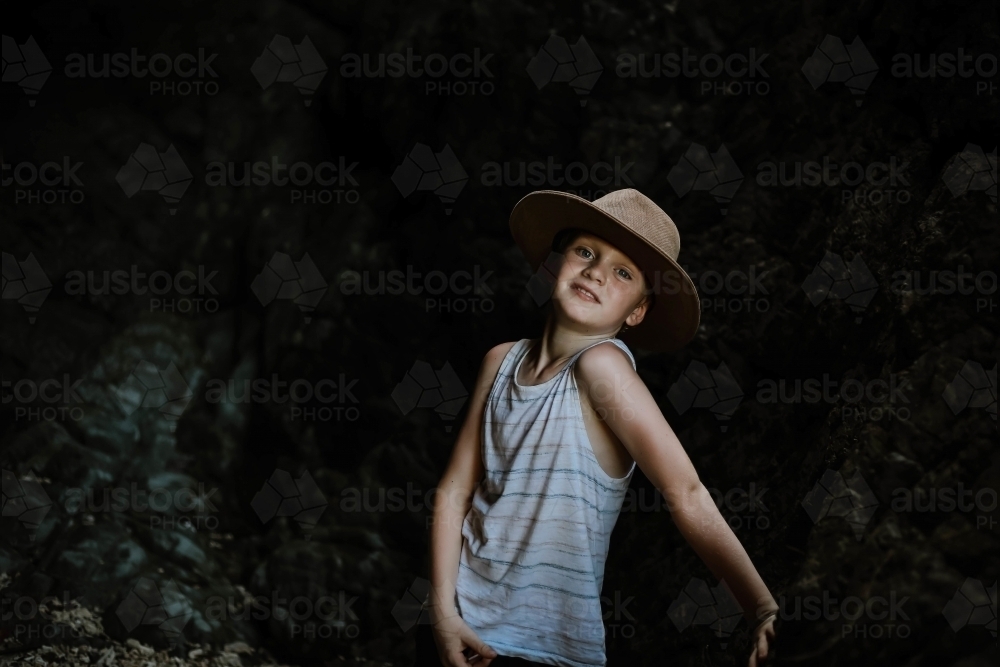 Moody image of young boy exploring dark cave in tropical north Queensland - Australian Stock Image