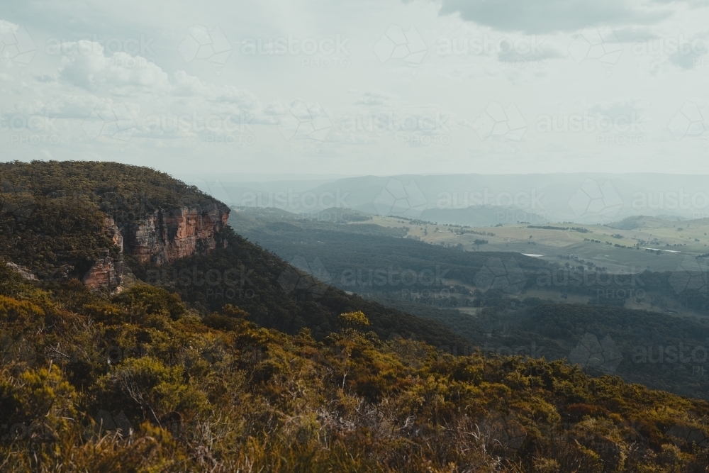 Moody valley view with a rocky cliff face as seen from Blackheath Lookout - Australian Stock Image