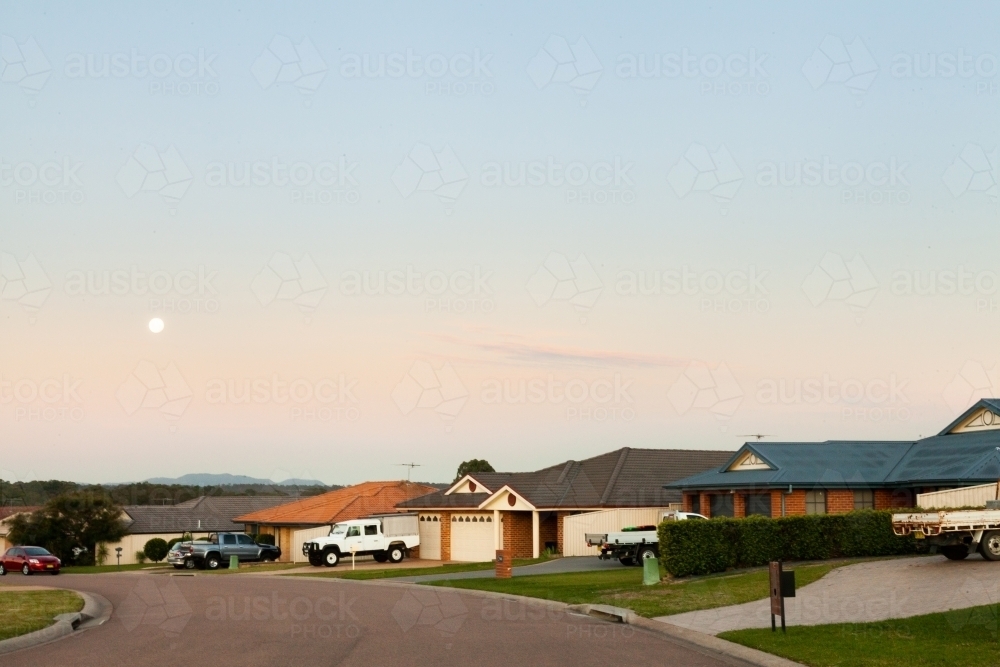 Moon in sky above sleepy town street and residential homes - Australian Stock Image