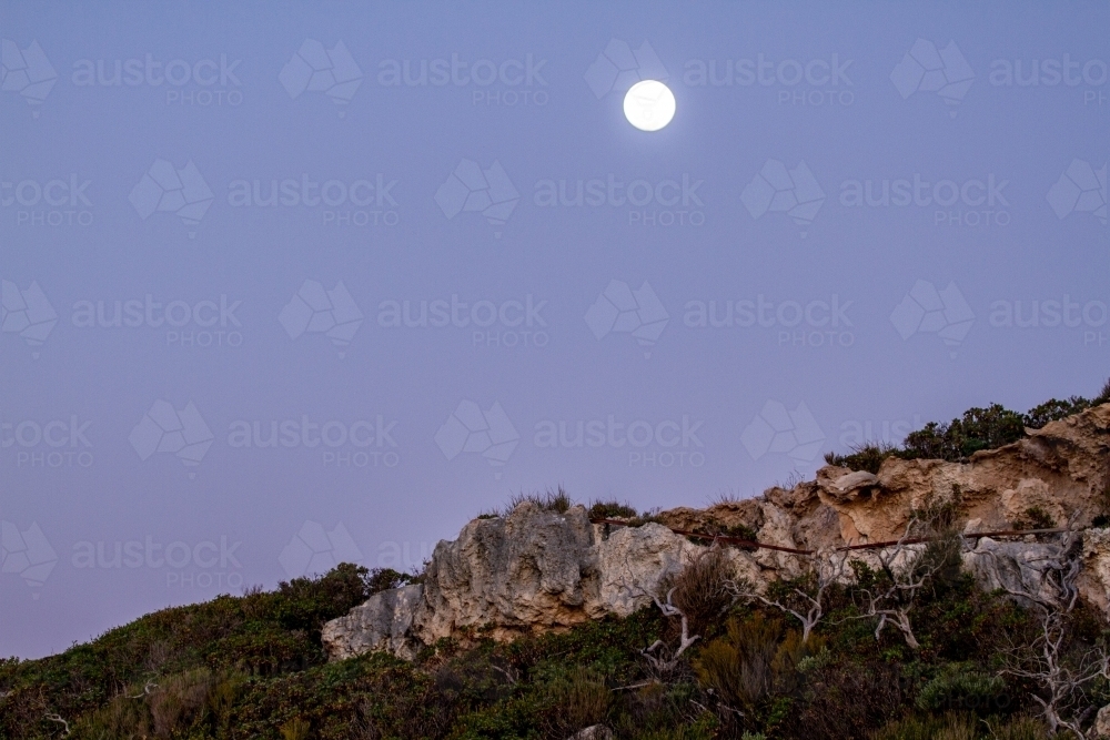 Moon rising above coastal cliff - Australian Stock Image