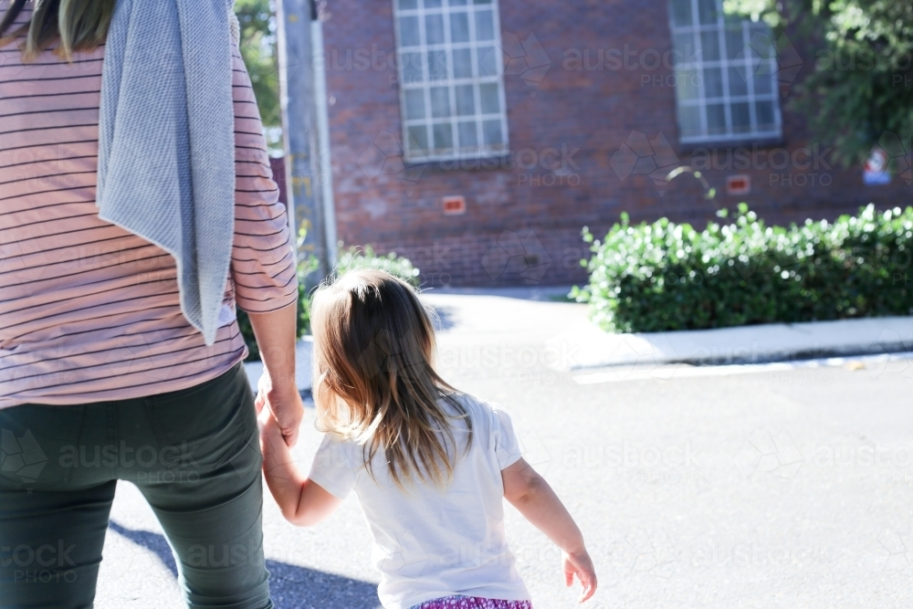 Mother and daughter holding hands while walking - Australian Stock Image