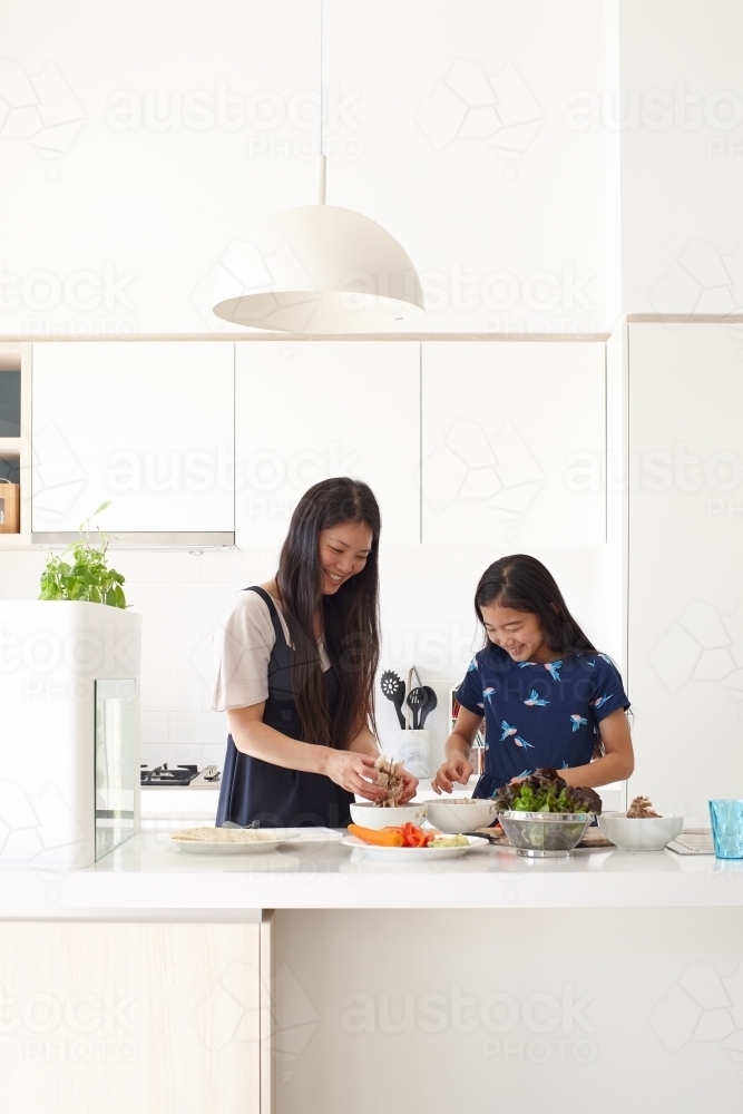 Mother and daughter in kitchen cooking together - Australian Stock Image