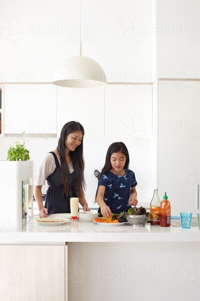 Mother and daughter in kitchen cooking together - Australian Stock Image