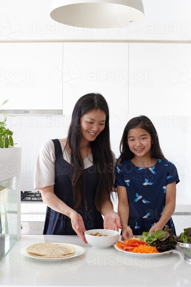 Mother and daughter in kitchen together preparing lunch - Australian Stock Image