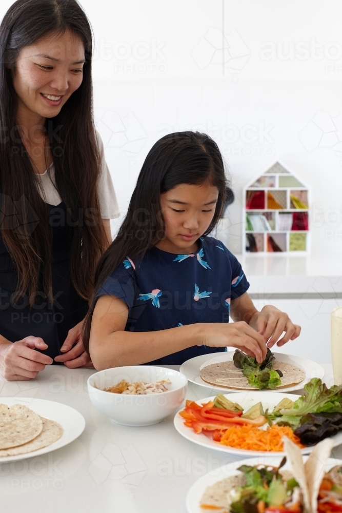 Mother and daughter in kitchen together preparing lunch - Australian Stock Image