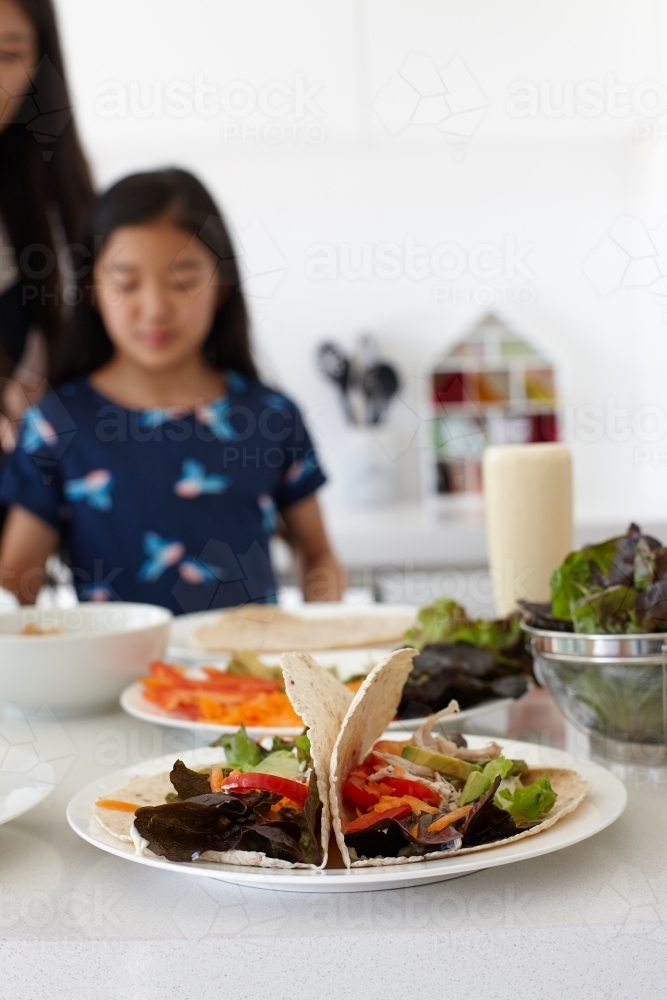 Mother and daughter in kitchen together preparing lunch - Australian Stock Image