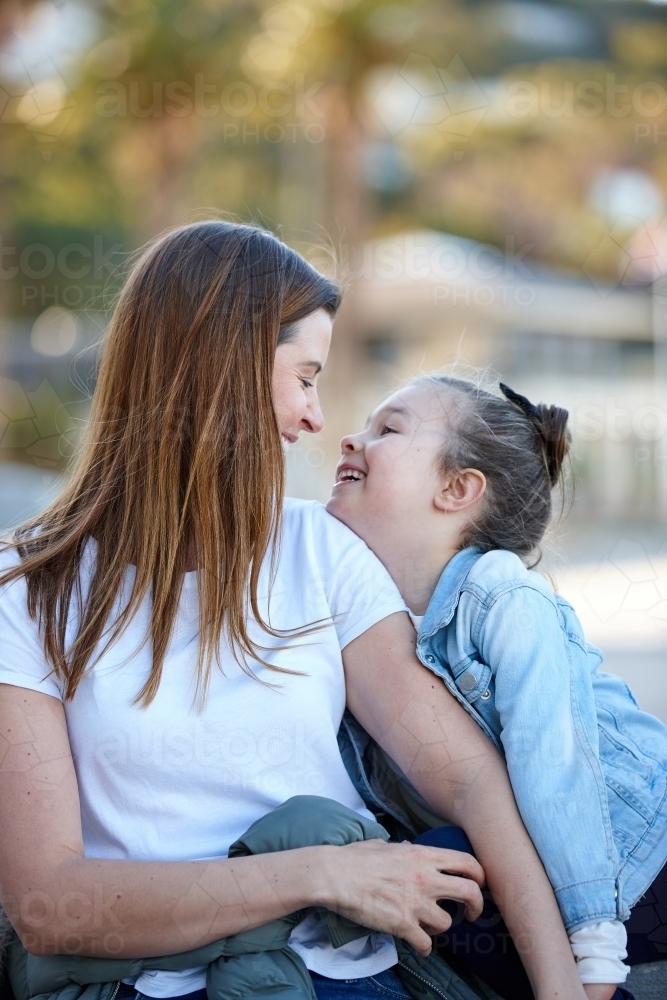 Mother and daughter sharing time laughing at beach promenade - Australian Stock Image