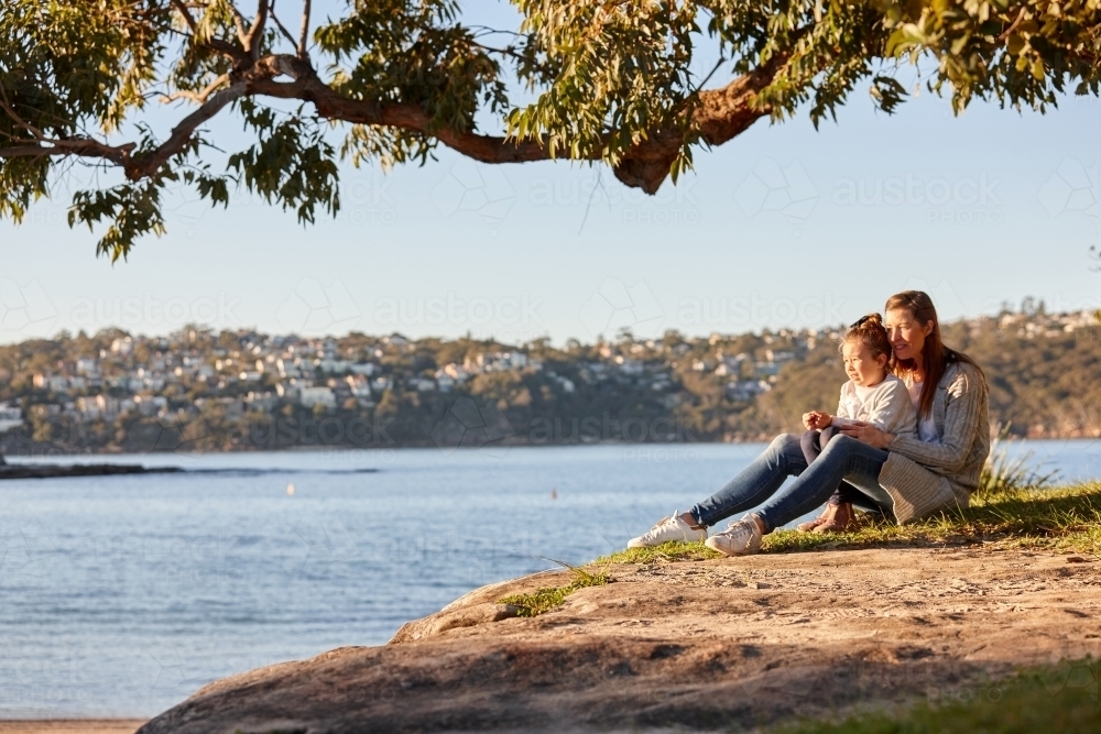 Mother and daughter sharing time together at headland over ocean - Australian Stock Image