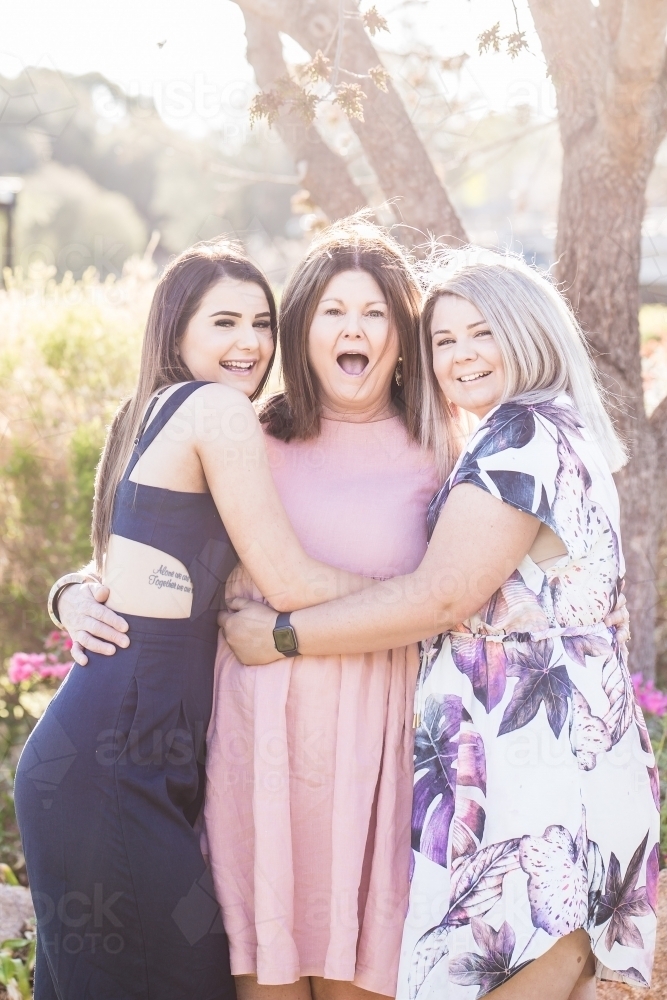 Mother and daughters hugging each other and laughing - Australian Stock Image