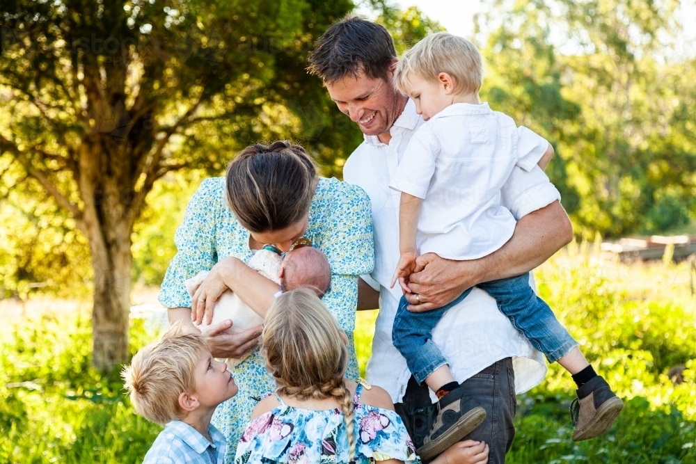 Mother and father with four children all looking at newborn sister - Australian Stock Image