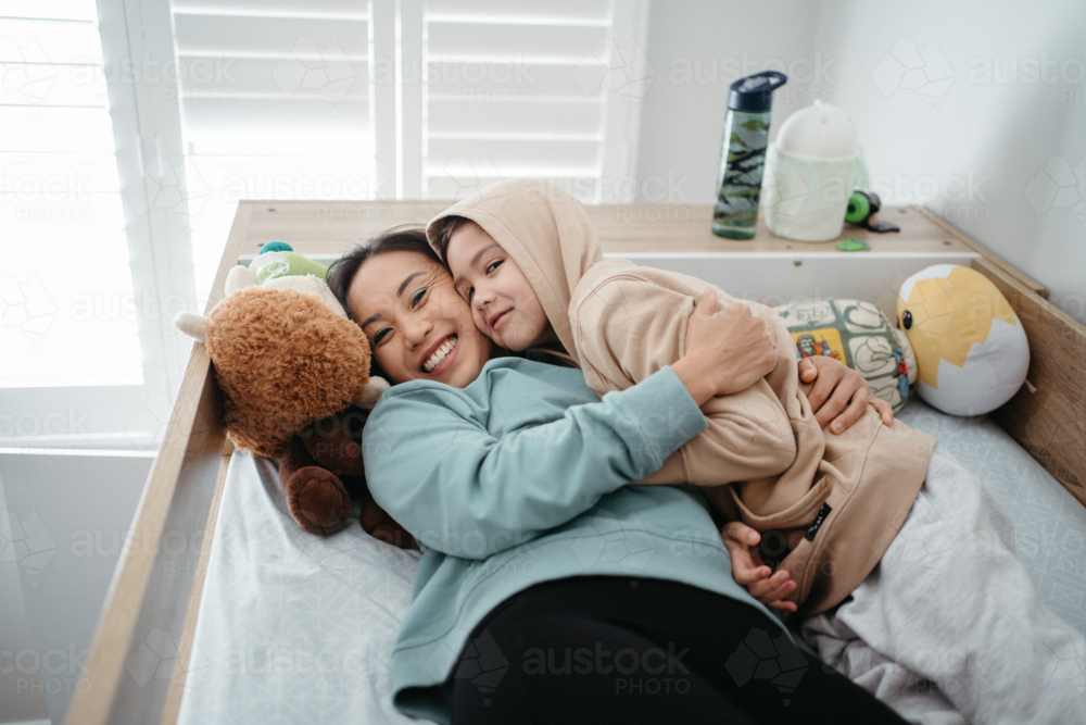 Mother and son are cuddling on top of bunk bed. - Australian Stock Image