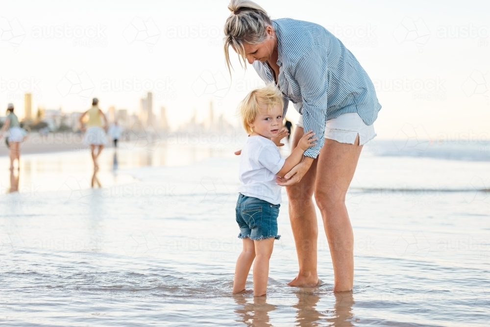 Mother and son playing in shallow water on Gold Coast beach - Australian Stock Image