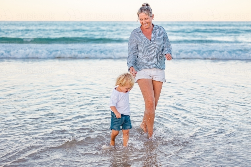 Mother and son playing in shallow water on Gold Coast beach - Australian Stock Image