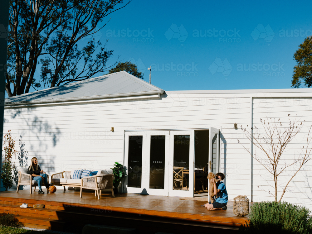 Mother and son spending time outside in the wooden deck. - Australian Stock Image