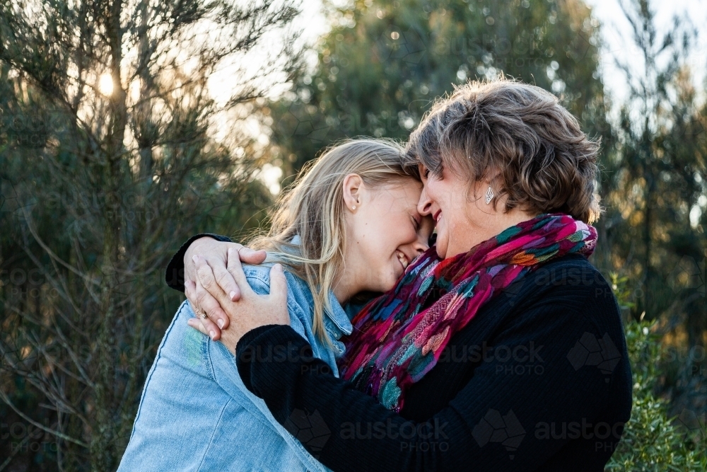 Mother and teenage daughter hug outside - Australian Stock Image