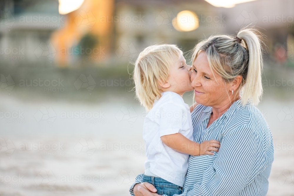 Mother and toddler son embracing on the sand of Gold Coast beach - Australian Stock Image