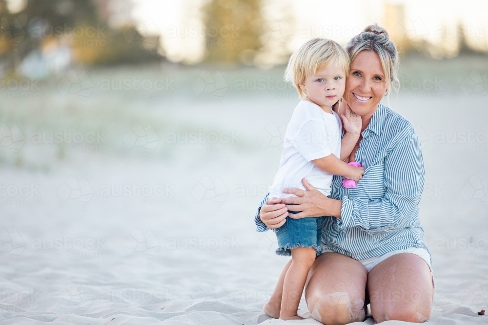 Mother and toddler son embracing on the sand of Gold Coast beach - Australian Stock Image