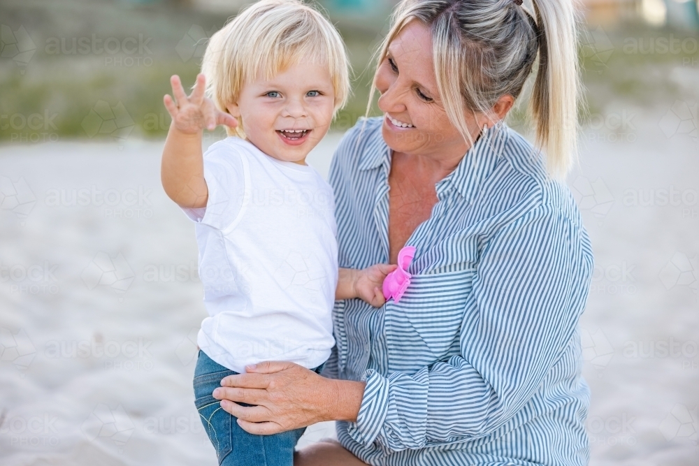 Mother and toddler son embracing on the sand of Gold Coast beach - Australian Stock Image
