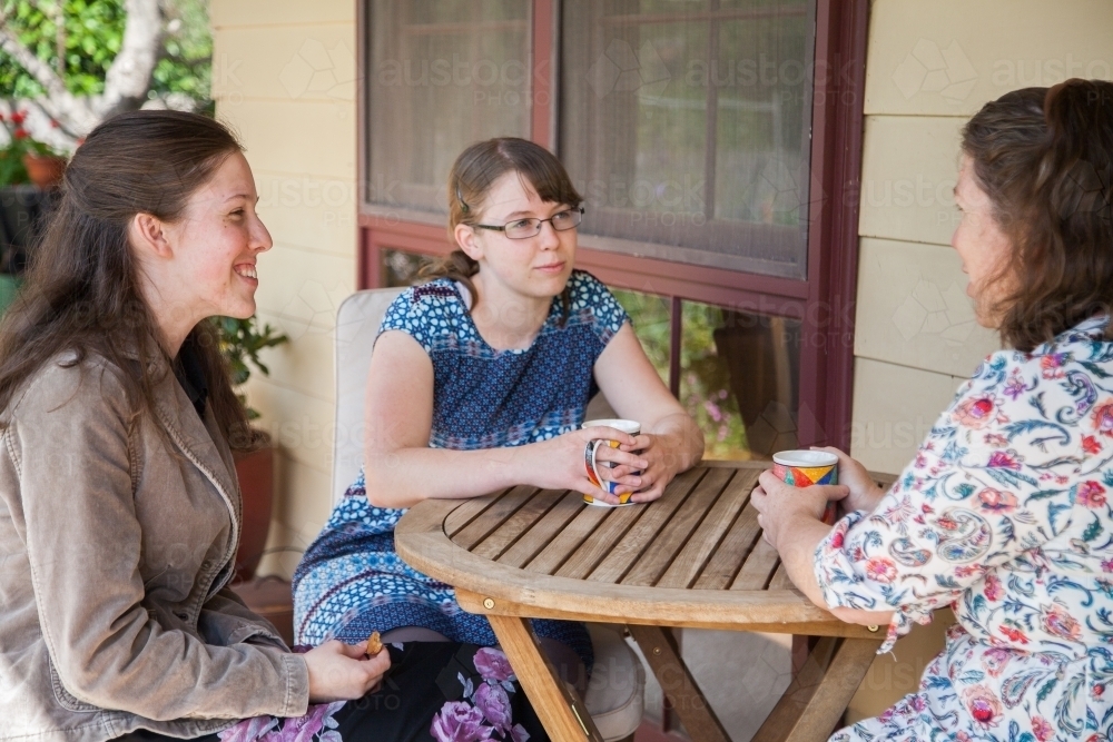 Mother and two teen daughters sitting together talking - Australian Stock Image