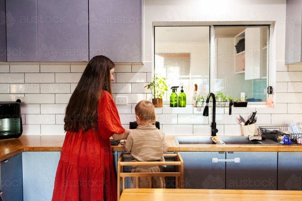 mother and young son cooking together in kitchen doing dinner prep - Australian Stock Image