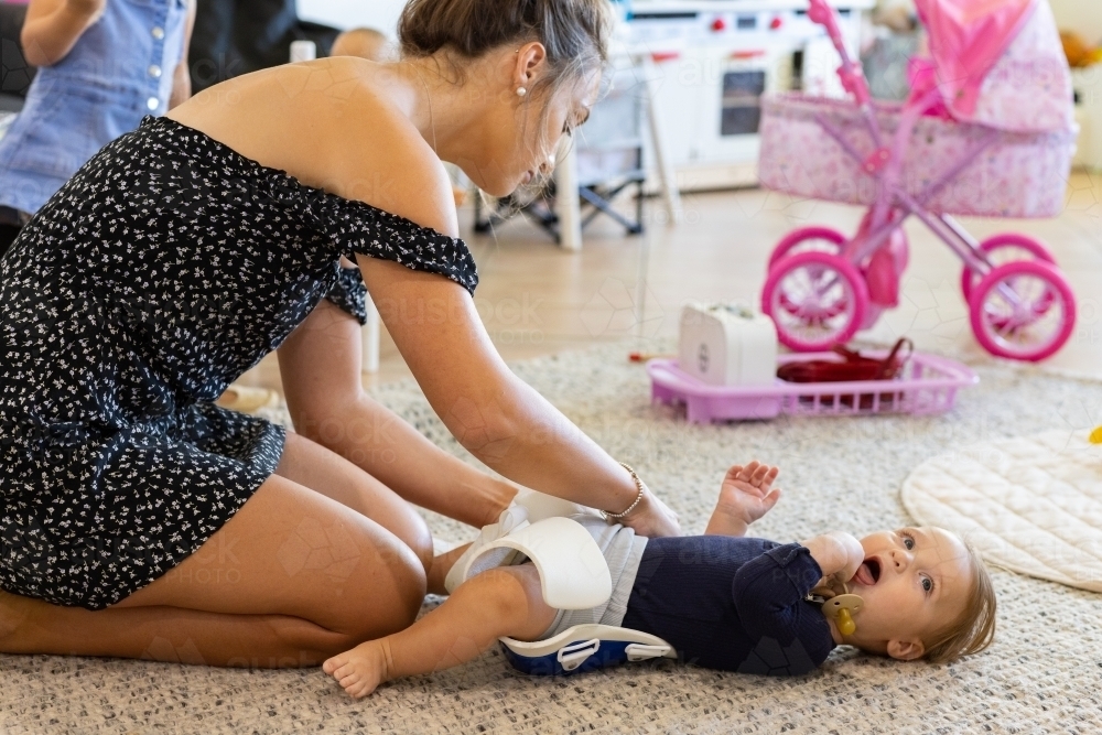 mother applying hip abduction brace to baby with hip dysplasia - Australian Stock Image