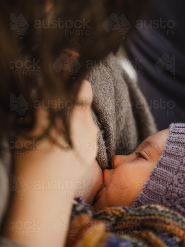 Mother breastfeeding baby wearing beanie - Australian Stock Image